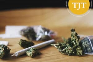 Marijuana buds, a rolled joint, and small plastic bags on a table, representing older possession and distribution cases that may have been expunged under N.J.S.A. 2C:52-6.1
